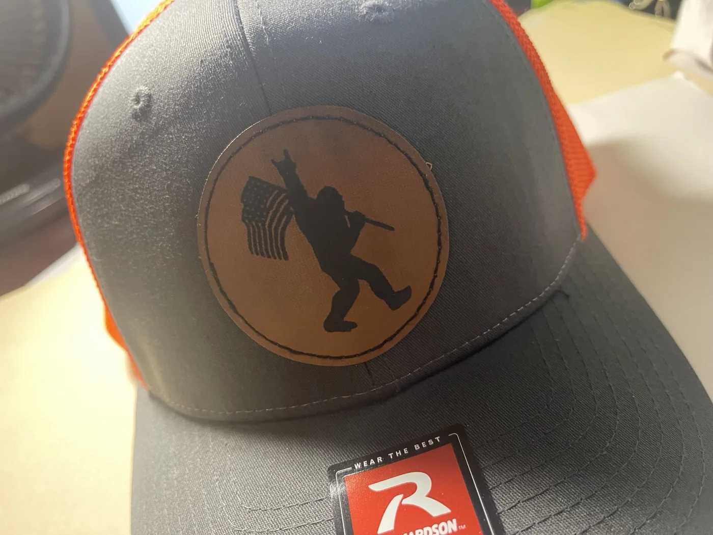 Black and orange trucker hat with round Bigfoot flag leather patch