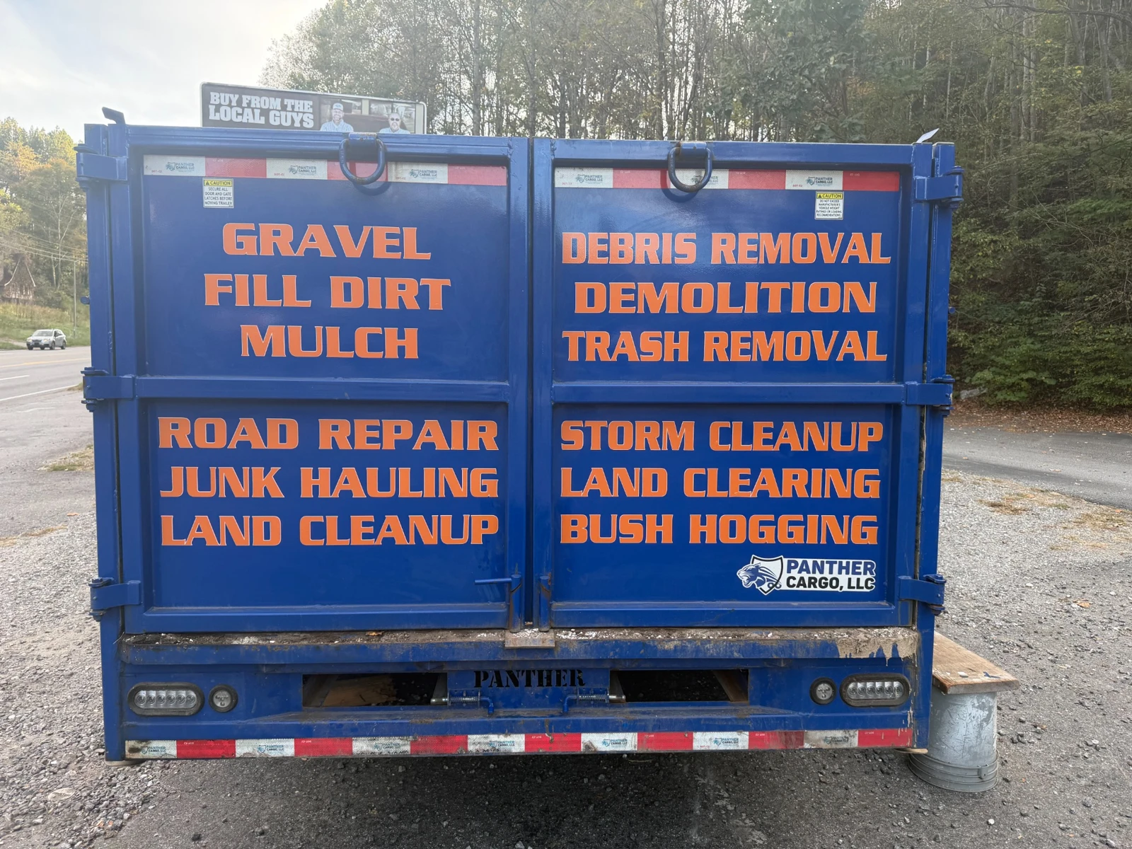 Orange service lettering arranged across the rear doors of a blue utility trailer