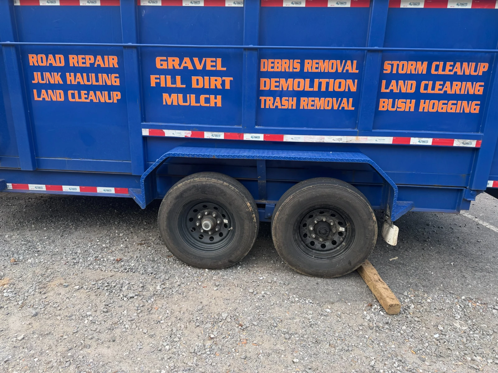 Orange service lettering across the side panels of a blue utility trailer