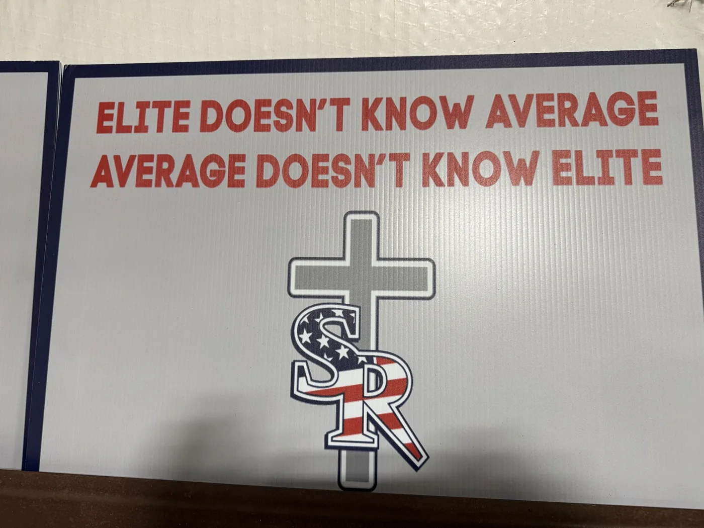White motivational school sign with red lettering and patriotic logo