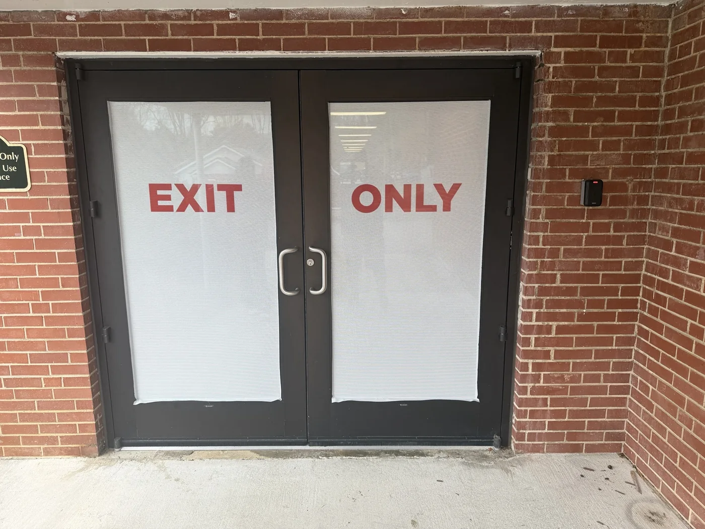 Red EXIT ONLY lettering on a pair of entrance doors