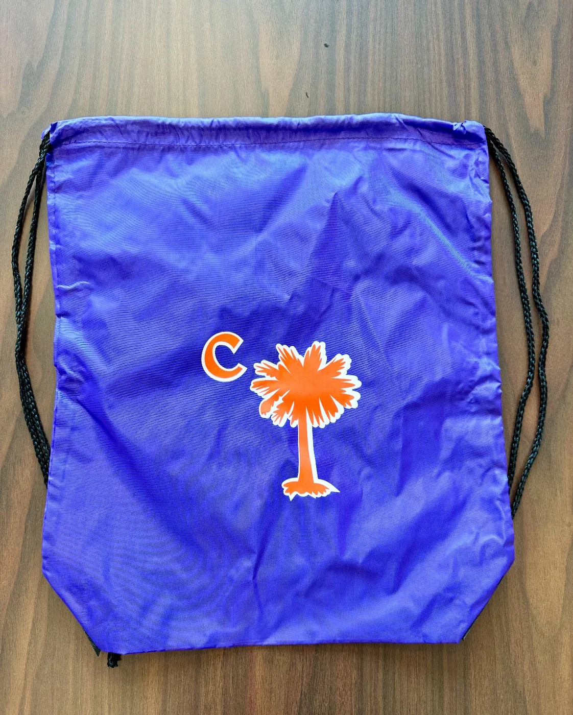 Purple drawstring bag printed with orange palmetto and C design
