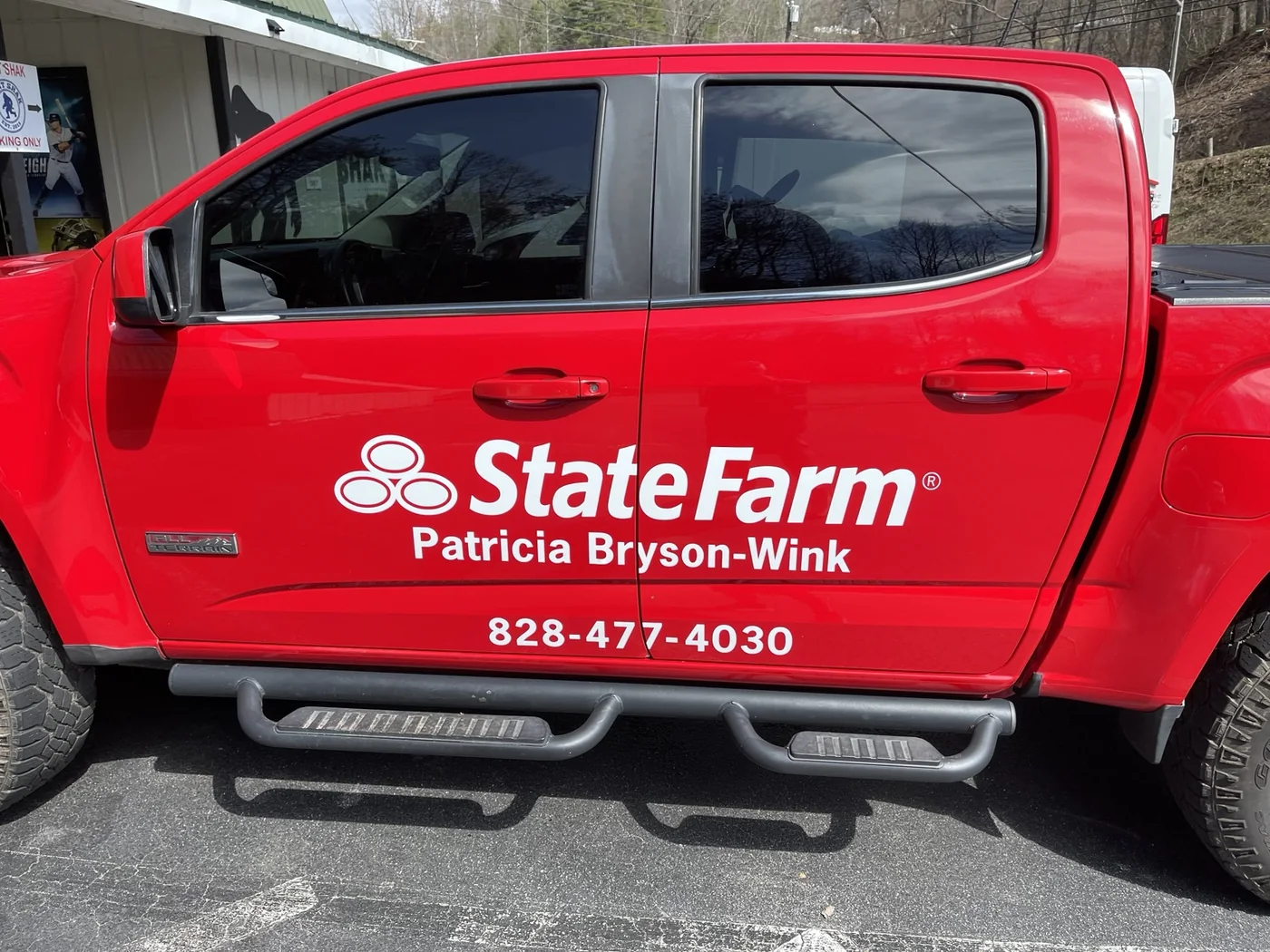 State Farm name and phone number lettered on a red pickup truck door