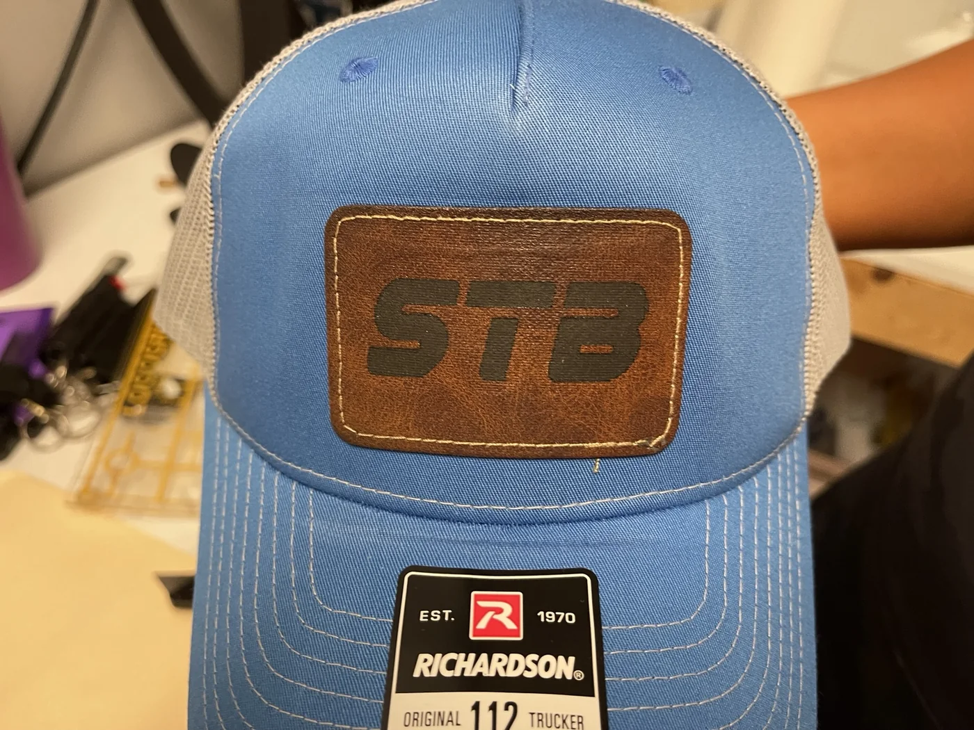 Blue STB trucker hat with stitched brown leather patch