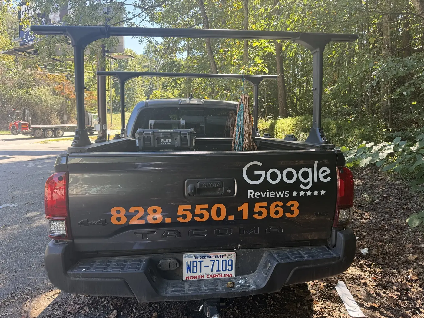 Orange phone number and white review lettering on a Toyota Tacoma tailgate